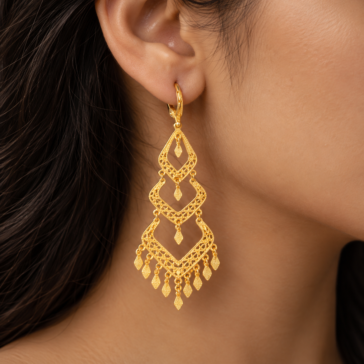 Three open diamond-shaped gold filigree tiers with dangling charms
