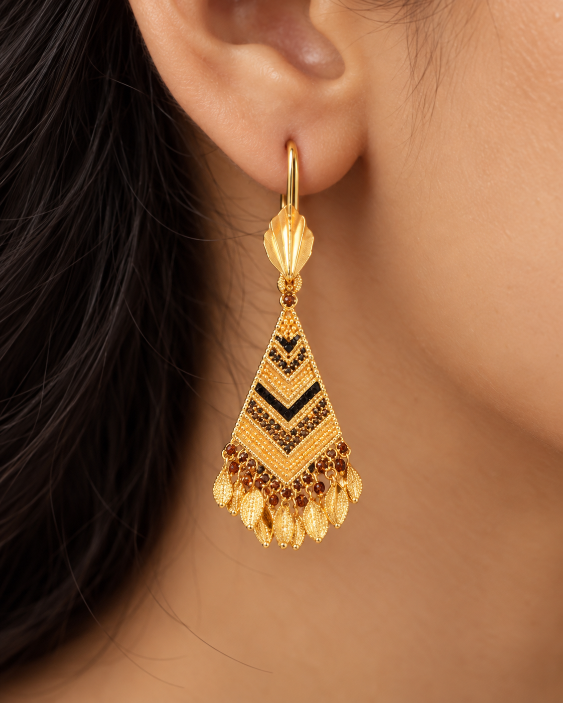 Long gold earrings with black and amber-toned stone chevrons and leaf fringe