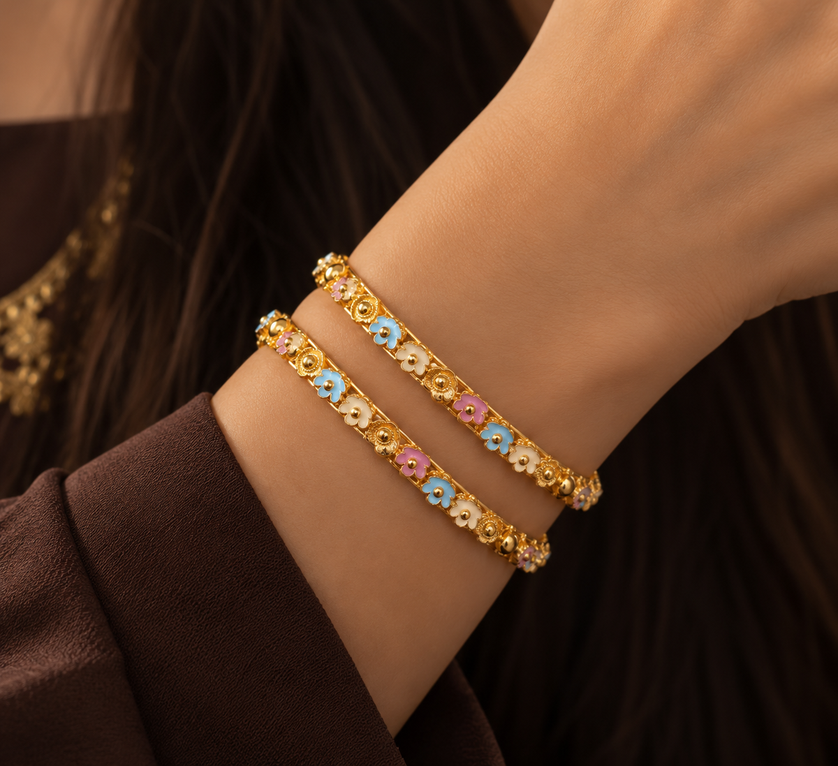 Pair of gold bangles with pastel enamel flowers in pink, blue and cream