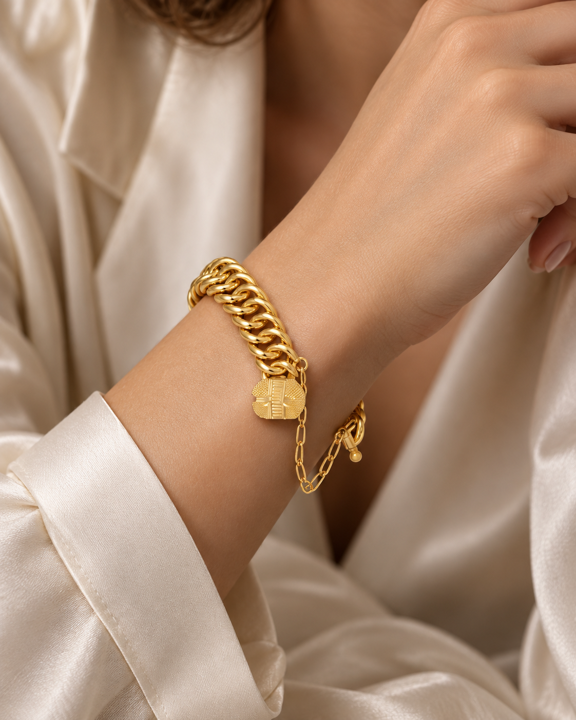 Polished gold curb bracelet with engraved padlock charm and safety chain
